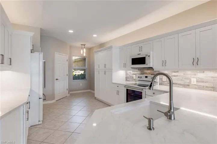Kitchen featuring white cabinetry, white appliances, recessed lighting, light tile patterned flooring, and hanging light fixtures