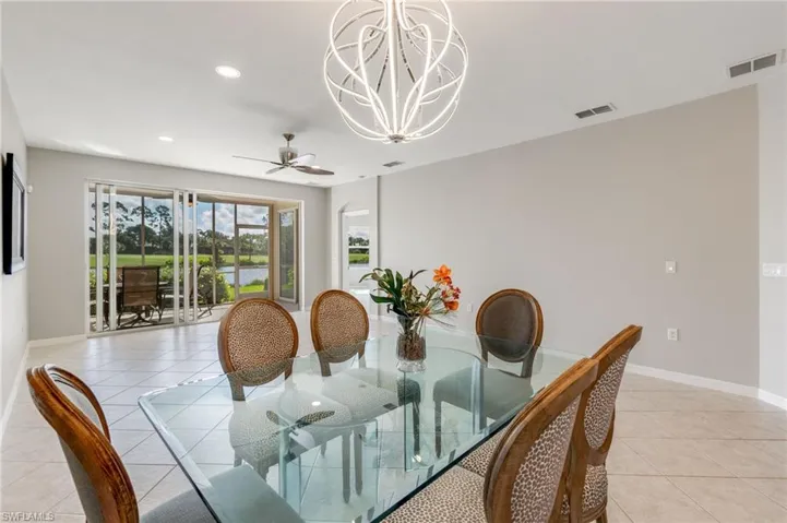 Dining space with light tile patterned floors, recessed lighting, a water view, a chandelier, and a ceiling fan