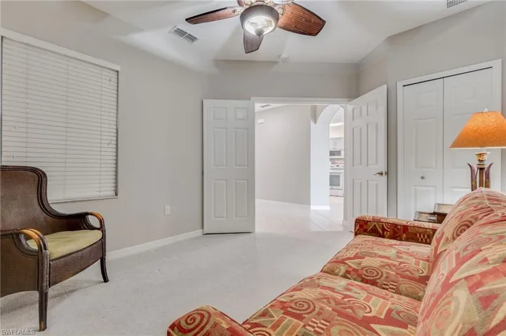 Sitting room featuring light colored carpet, arched walkways, and ceiling fan
