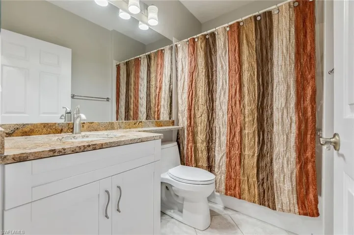Full bathroom with vanity, light tile patterned floors, and a shower with curtain