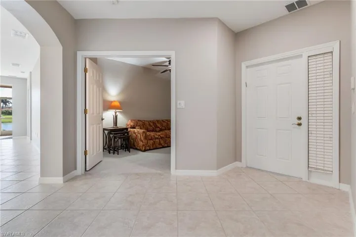 Entrance foyer with light tile patterned floors, arched walkways, and a ceiling fan
