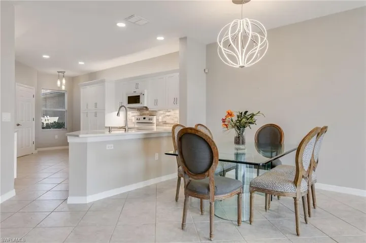 Dining area with light tile patterned floors, recessed lighting, and a chandelier