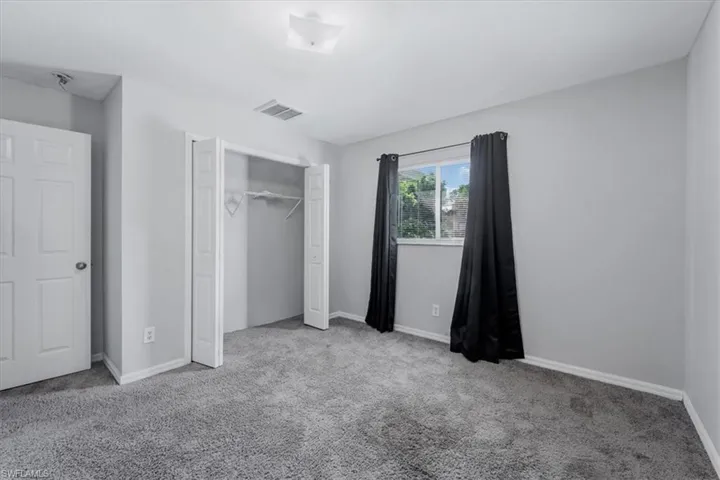 Carpeted room featuring a double-pane window, bi-fold closet doors, a white interior door, and a ceiling-mounted light fixture