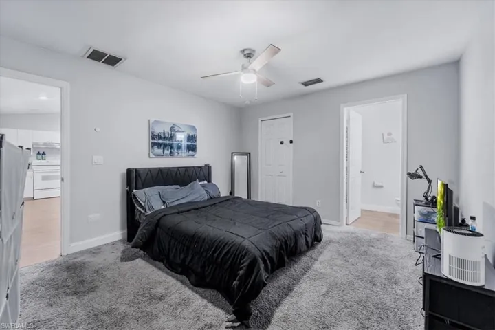 Spacious room featuring light gray walls, plush gray carpeting, a built-in ceiling fan, and two interior doorways