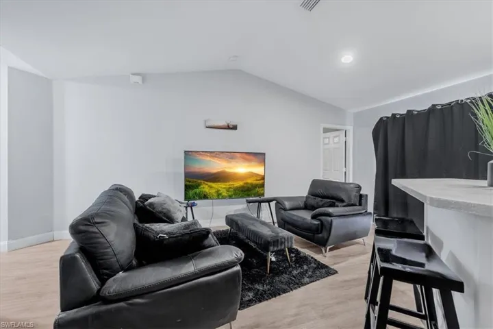 Living area featuring wood-finish flooring, vaulted ceilings, and recessed lighting
