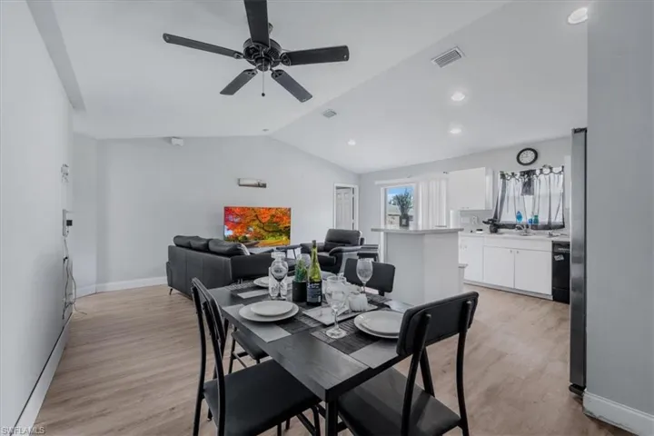 Open-concept living space featuring wood-finish flooring, vaulted ceilings, recessed lighting, and a modern ceiling fan