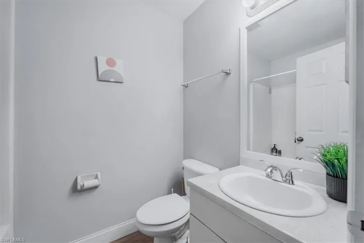 Bathroom featuring a white vanity with an integrated sink, chrome faucet, and expansive wall mirror