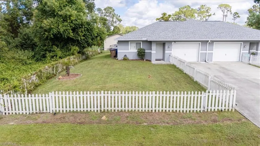 Gray exterior with a dark gray shingle roof and a white picket fence enclosing the front yard