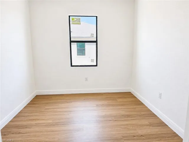 Neutral painted walls with wood-finish flooring and white baseboards