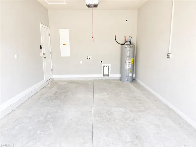 Spacious garage featuring a concrete floor, painted walls, white trim, and a water heater installation
