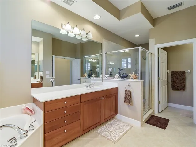 Bathroom featuring shower with separate bathtub, vanity, and tile floors