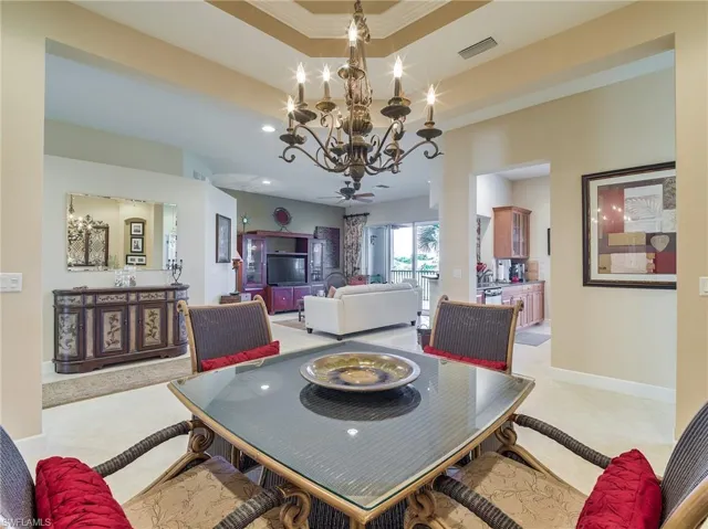 Tiled dining room featuring a notable chandelier, a raised ceiling, and crown molding