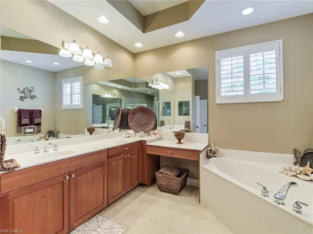 Bathroom with a wealth of natural light, a washtub, dual sinks, and large vanity