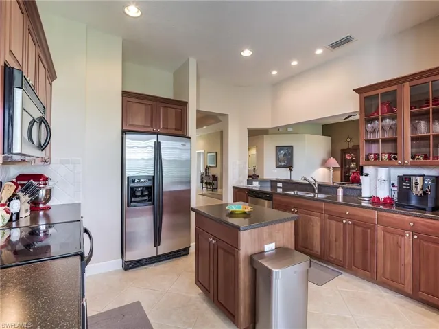Kitchen with a center island, appliances with stainless steel finishes, backsplash, sink, and light tile flooring