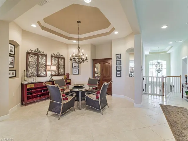 Dining area with a notable chandelier, light tile floors, and a raised ceiling