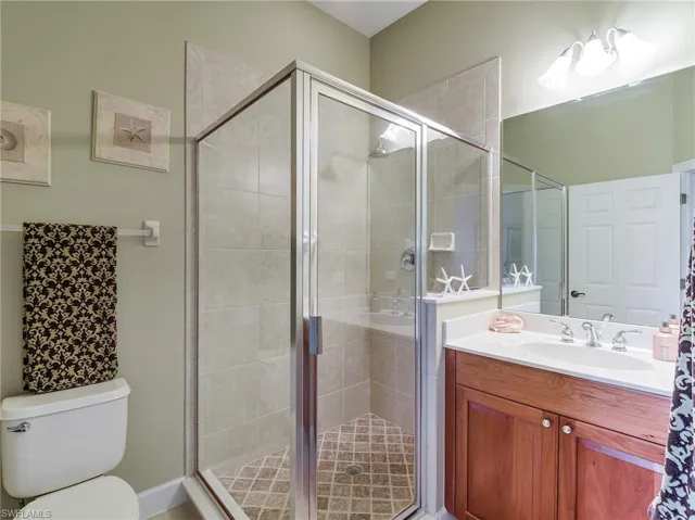 Bathroom featuring a shower with door, vanity, and toilet