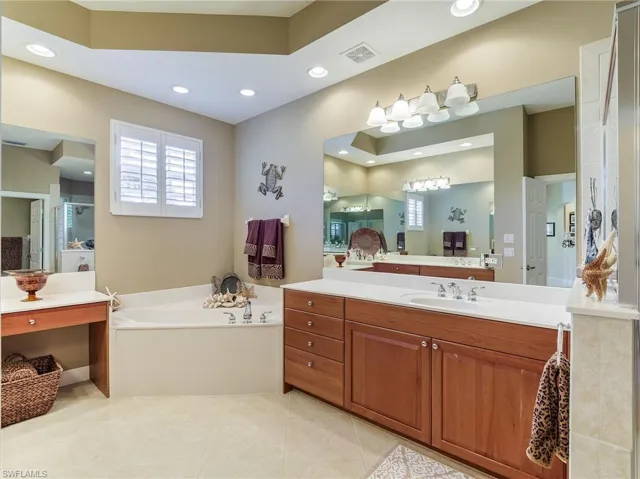 Bathroom with tile flooring, vanity, and a bath to relax in