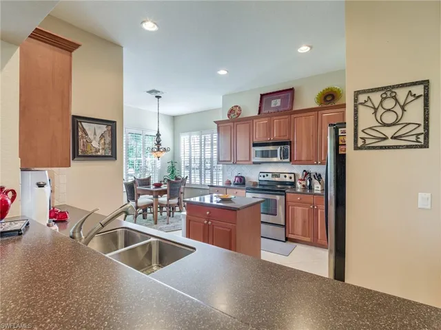 Kitchen with a kitchen island, appliances with stainless steel finishes, sink, tasteful backsplash, and light tile floors