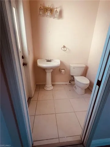 Half bathroom featuring toilet, tile patterned floors, and baseboards