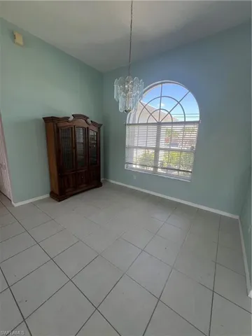 Unfurnished dining area with a notable chandelier, tile patterned flooring, and baseboards