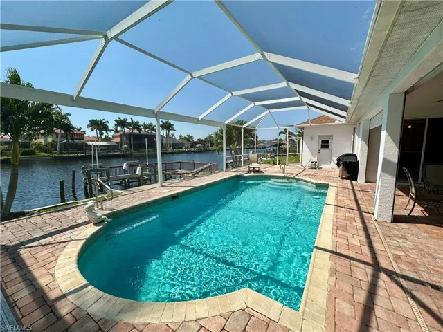 Outdoor pool with a dock, a water view, boat lift, a patio, and a lanai