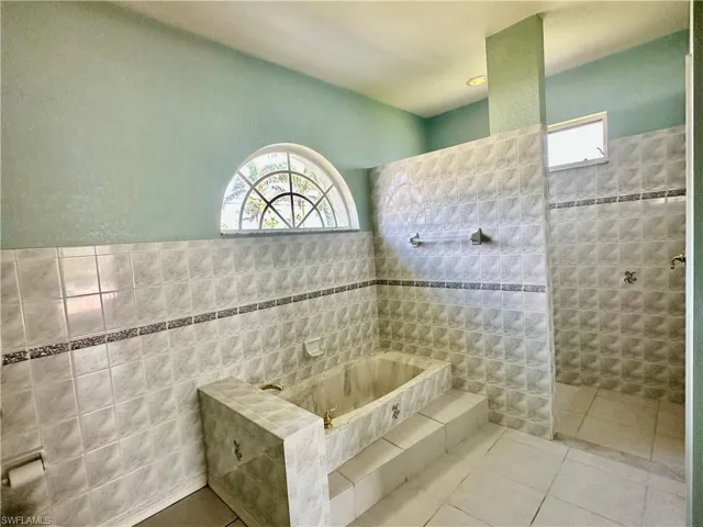 Full bathroom with tile walls, tile patterned floors, a wealth of natural light, and a walk in shower