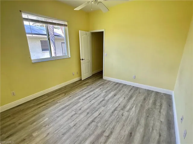 Spare room featuring ceiling fan, baseboards, and wood finished floors