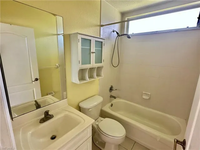 Full bath featuring a textured wall, toilet, vanity, a textured ceiling, and bathtub / shower combination