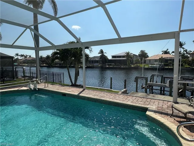 Outdoor pool featuring glass enclosure, a residential view, a patio area, and a water view