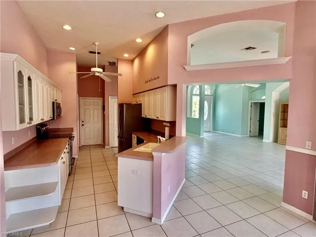 Kitchen featuring light tile patterned flooring, a ceiling fan, stainless steel appliances, and a sink