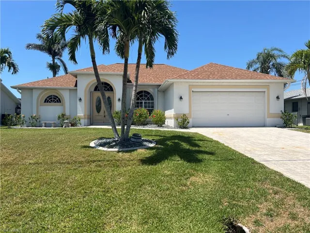 View of front of home with a garage, stucco siding, driveway, and a front lawn