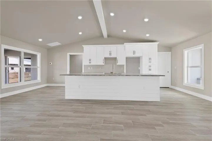 Kitchen with plenty of natural light, white cabinetry, wood finish floors, recessed lighting, and beamed ceiling