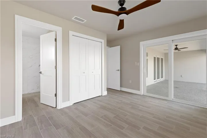 Unfurnished bedroom with wood tiled floors, a closet, a ceiling fan, and access to exterior