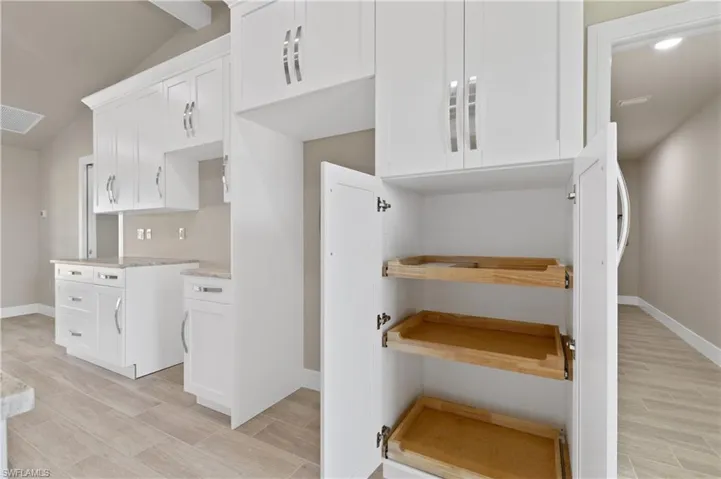 Kitchen featuring white cabinets, wood finish floors, and lofted ceiling