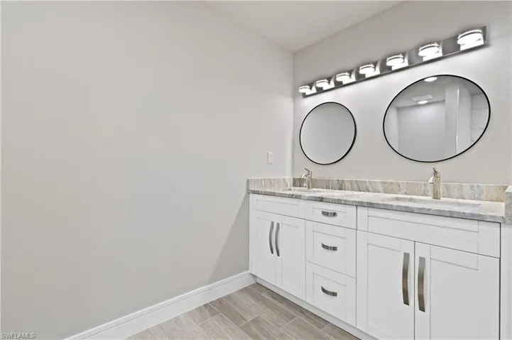 Full bath with double vanity and wood finish floors
