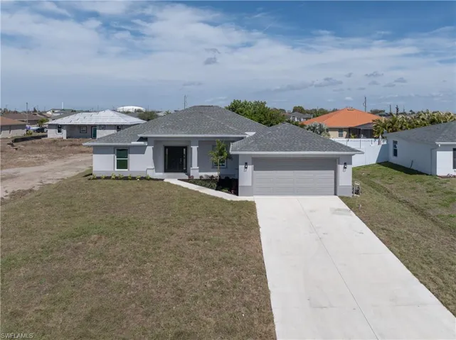 View of front of property featuring a front lawn, a shingled roof, driveway, and stucco siding