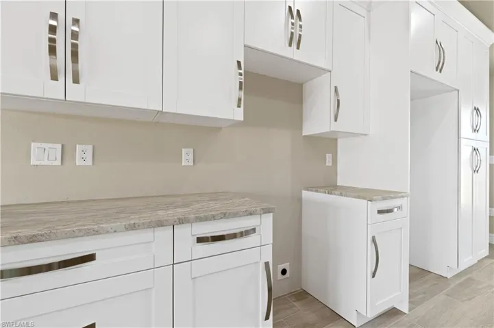 Kitchen with white cabinetry, light stone countertops, and wood tiled floors