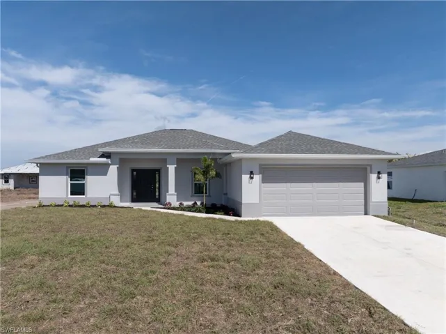 View of front of house with stucco siding, a front lawn, concrete driveway, and an attached garage