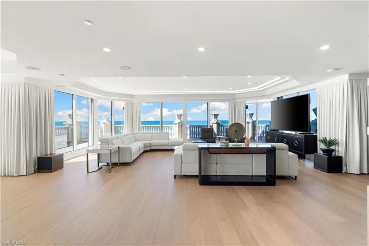 Living room featuring a tray ceiling, light wood-type flooring, and floor to ceiling windows