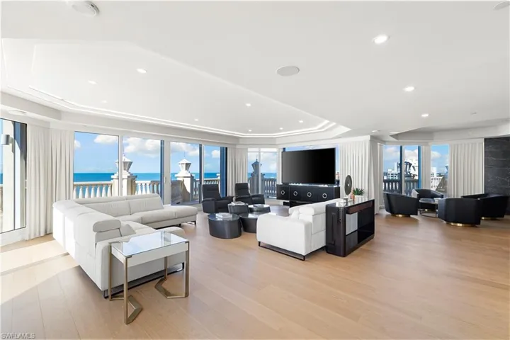 Living area featuring floor to ceiling windows, a raised ceiling, light wood-style floors, and recessed lighting