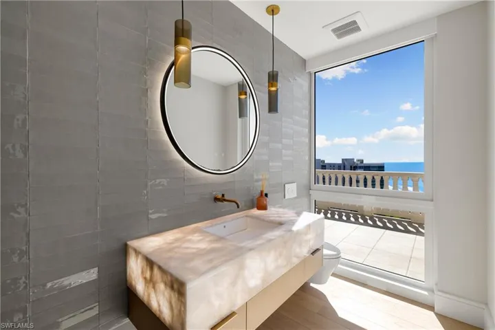 Half bathroom featuring tile walls, vanity, a water view, and wood finished floors