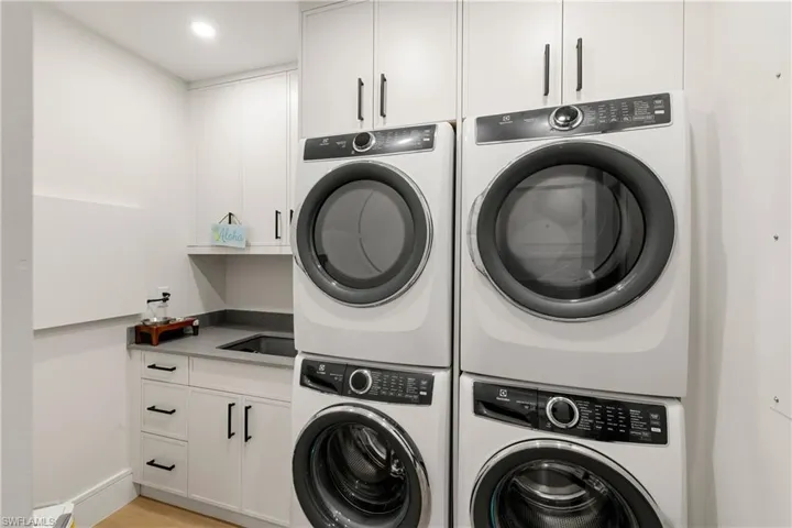 Laundry room featuring cabinet space, light wood finished floors, and recessed lighting