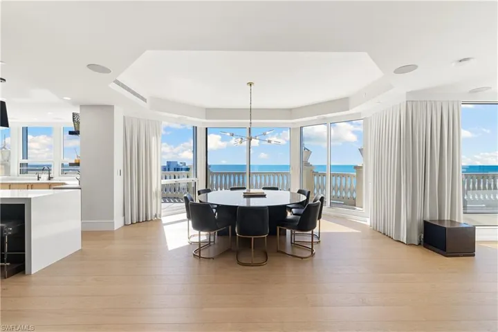 Dining area with a tray ceiling, light wood-type flooring, a water view, and hanging lights