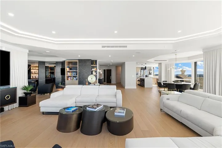 Living area featuring light wood finished floors, a tray ceiling, built in features, and recessed lighting