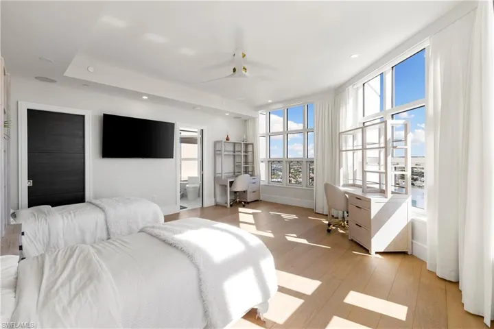 Bedroom with built in desk, recessed lighting, light wood-style flooring, and ensuite bath
