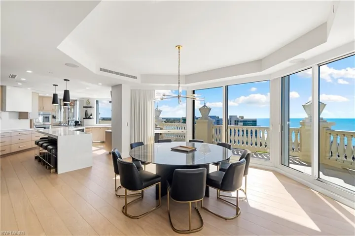 Dining room featuring light wood-style flooring, a raised ceiling, a water view, and hanging lights