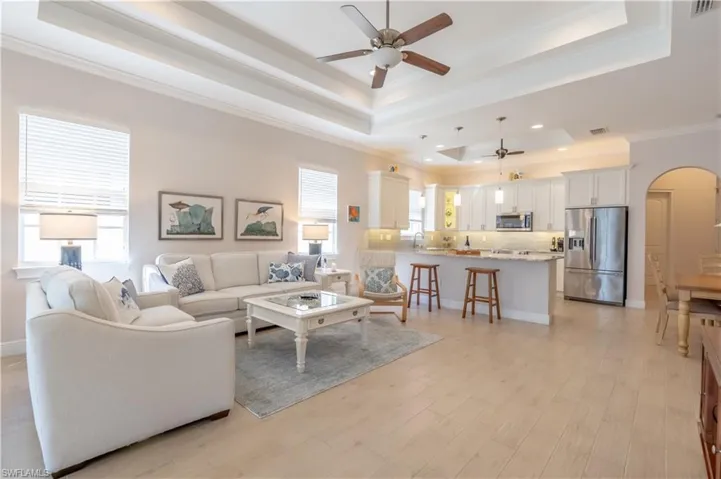 Living room featuring ceiling fan, crown molding, and a raised ceiling