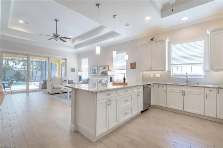 Kitchen featuring a raised ceiling, white cabinetry, and ceiling fan