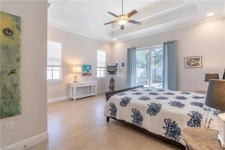Primary Bedroom featuring a tray ceiling, multiple windows.