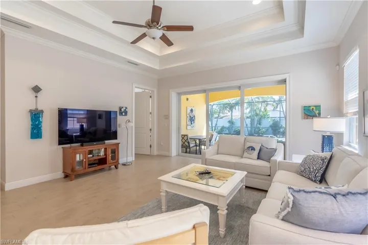 Living room featuring a tray ceiling, crown molding, and ceiling fan.